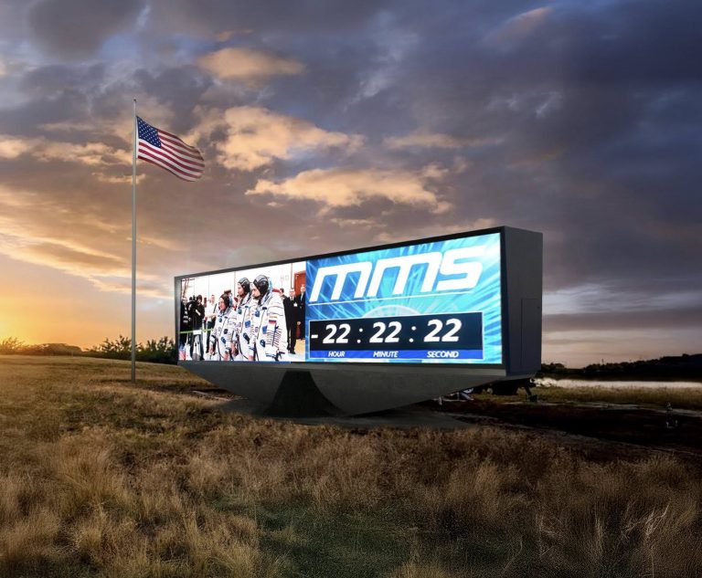 Large outdoor LED billboard displaying for NASA countdown timer in an open landscape with American flag at sunset in Florida