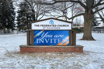 Outdoor LED sign at a church displaying welcome message in a snowy roadside setting with trees and open space in Washington