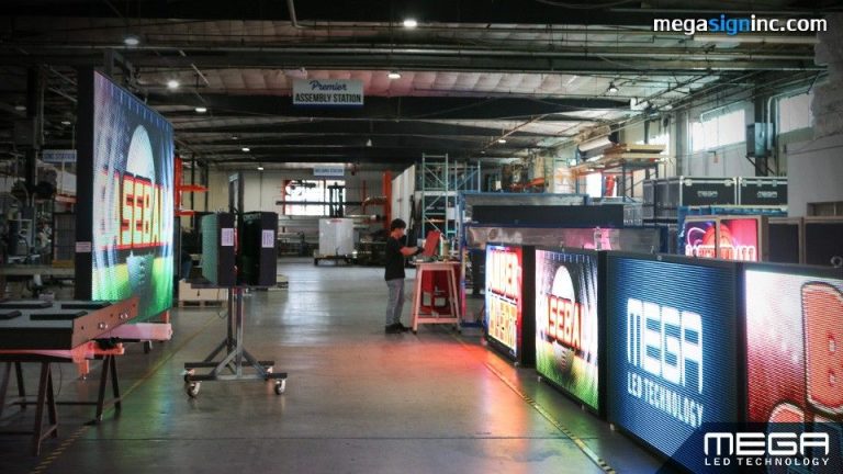 Large commercial LED display screens being assembled and tested inside a digital signage manufacturing facility.